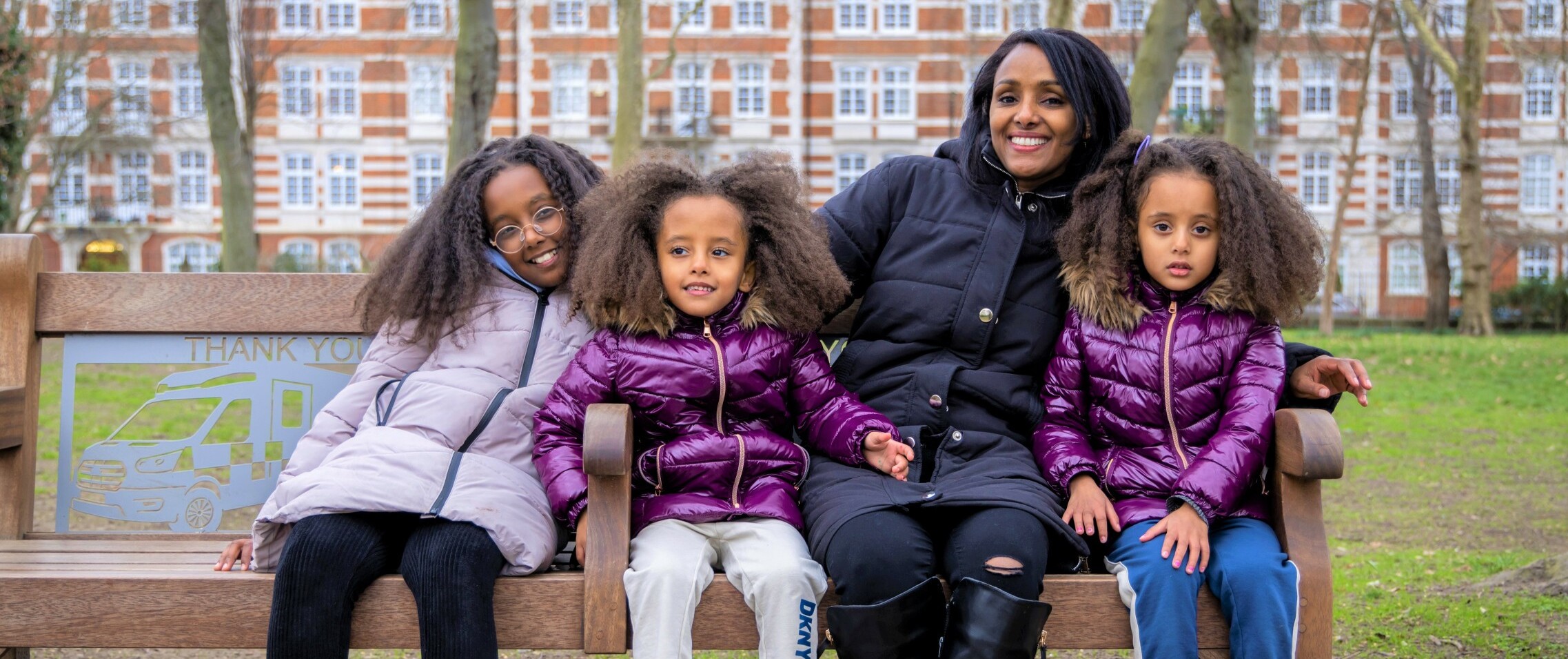 Family sitting on a bench with flats in the background