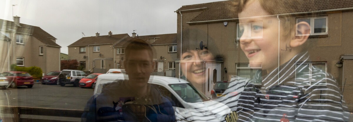 A Family is reflected looking out through their window
